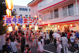 写真：西牛房まつりの看板。ちょうちんに明かりがともる。