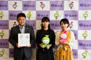 写真：サイン入りの色紙を市長に手渡す様子